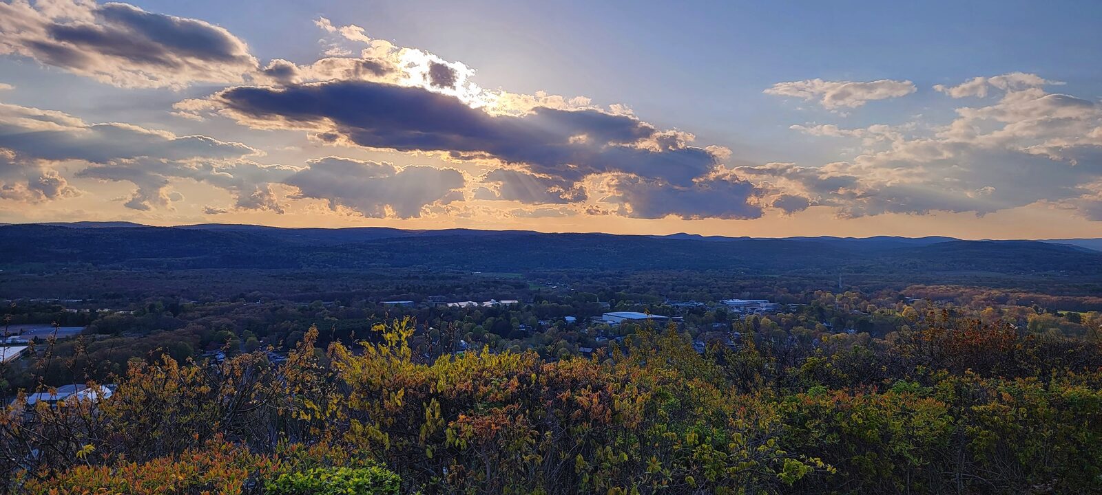 A picture of the sun behind clouds with a view of western Massachusetts from Mt. Sugarloaf